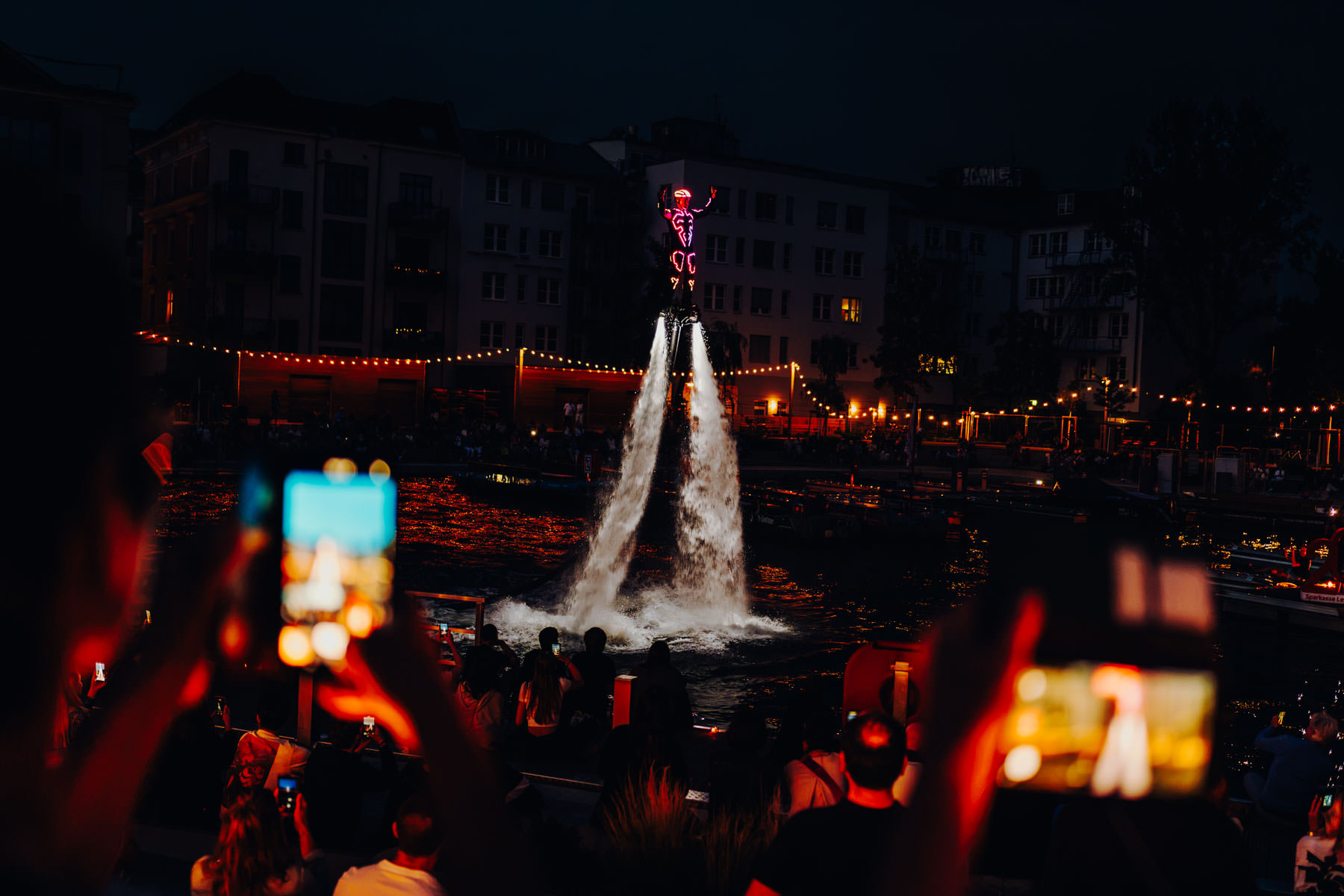 Eventfotograf Leipzig Flying Gordon Stadthafen Flyboard-Show bei Nacht: Eine Person in einem LED-Anzug schwebt auf Wasserstrahlen über dem Wasser zum Hafenfest 2026 in Leipzig