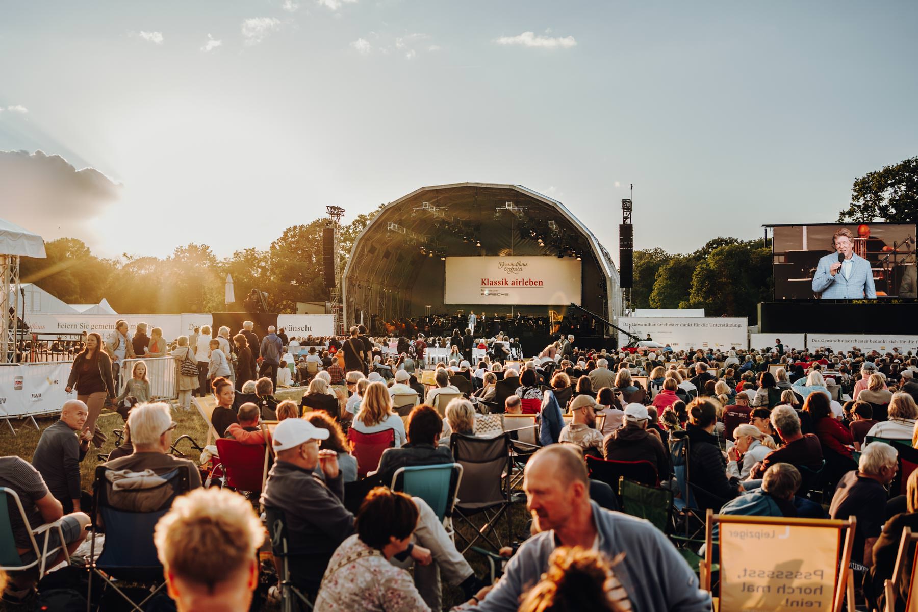 Eventfotograf Leipzig Klassik Airleben Publikum bei Sonnenuntergang auf einer Wiese vor der Bühne des Open-Air-Konzerts Klassik airleben im Rosenthal Leipzig
