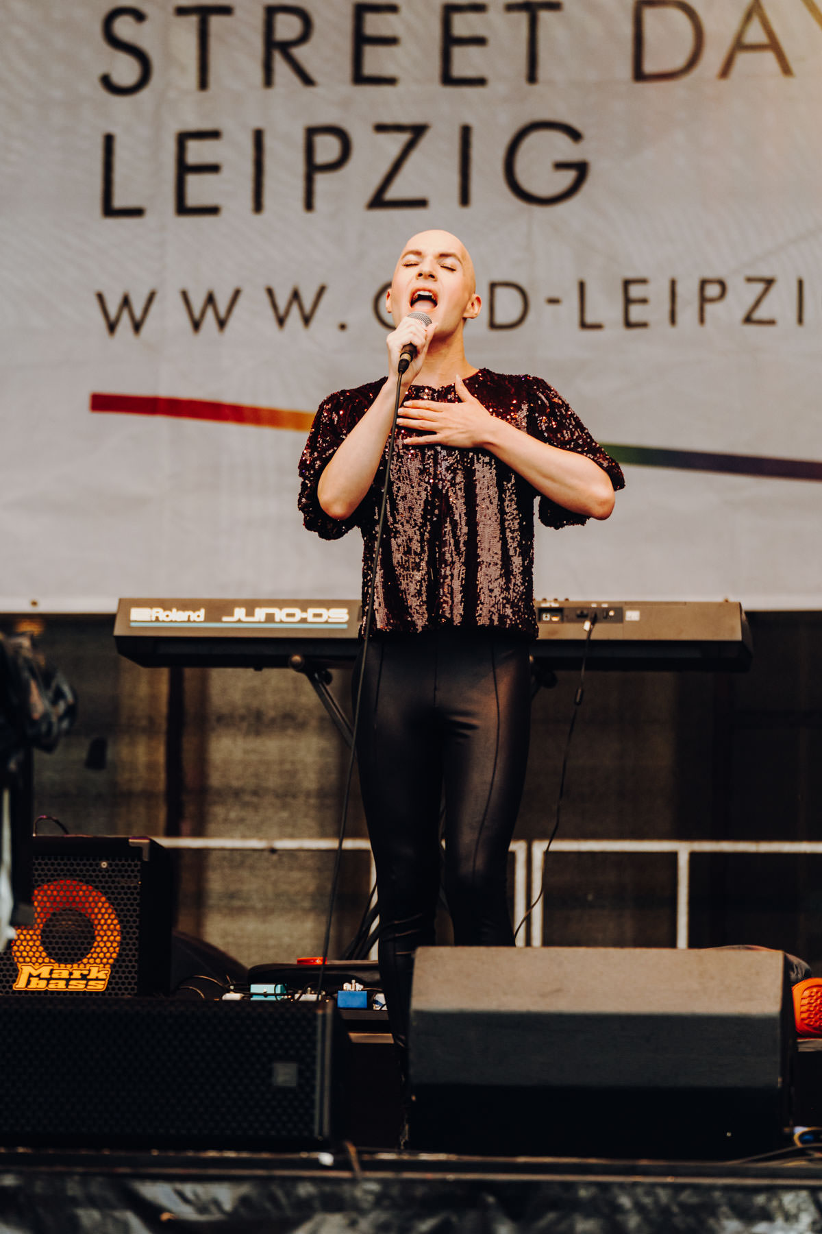 Eventfotograf Leipzig Konzert CSD Augustusplatz Sänger mit Glatze im Paillettenoberteil singt auf einer Bühne beim CSD Leipzig